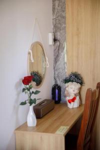 a desk with a vase of flowers and a mirror at LUA Farmstay in Bà Rịa