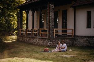 a couple sitting on the grass in front of a house at Pod Skalou in Temeš