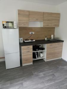 a kitchen with a white refrigerator and wooden cabinets at Apartmán Slepička in Weissbach