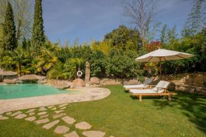 a pool with two lounge chairs and an umbrella at Villa Oasis Madrid in Batres