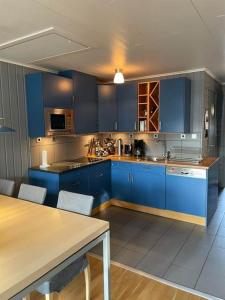a kitchen with blue cabinets and a table with chairs at Central Apartment with Sauna & Balcony in Åre
