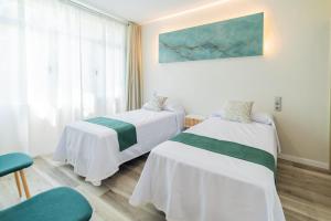 a hospital room with two beds and a chair at Apartamentos El Real in Mota del Cuervo