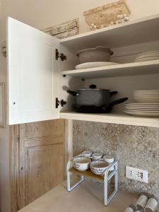 a kitchen with white cabinets and dishes on a shelf at DimoraStella in Pezze di Greco +7 photos