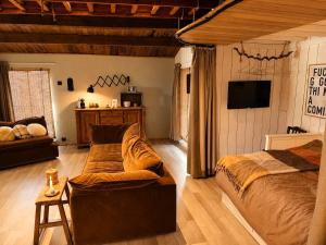 a bedroom with a bed and a couch and a tv at Little Bali in Geel
