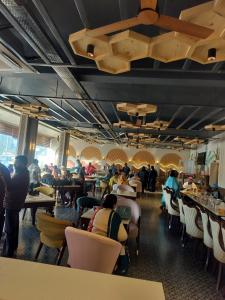 a restaurant with people sitting at tables and chairs at Vani Hotel Golden Petals in Una