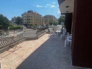 a patio with white chairs and tables and buildings at Angel in Primorsko +15 photos