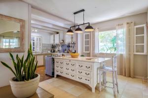 a kitchen with a large white island with a table at Villa avec piscine à Saint-Gilles les Bains, 260 m², 9 pers. in Saint-Gilles-les-Bains +12 photos