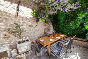 a wooden table and chairs in a patio with flowers at Elegant villa in Podgora with private pool and sea view in Podgora