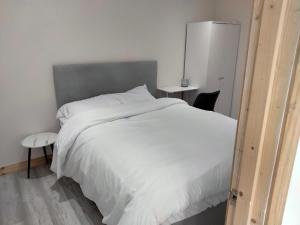 a bedroom with a large white bed and a chair at The Place CABIN in Coleraine