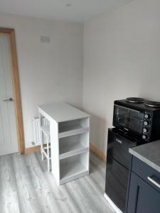 a kitchen with a white table and a microwave at The Place CABIN in Coleraine