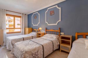 a bedroom with three beds and a blue wall at Spacious apartment with sea view in La Mata - 75 m² - Pool in La Mata