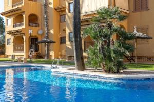 a swimming pool in front of a building with palm trees at Spacious apartment with sea view in La Mata - 75 m² - Pool in La Mata