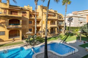 an apartment with a swimming pool in front of a building at Spacious apartment with sea view in La Mata - 75 m² - Pool in La Mata