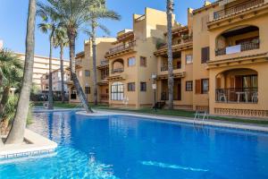 a swimming pool in front of a building with palm trees at Spacious apartment with sea view in La Mata - 75 m² - Pool in La Mata +12 photos