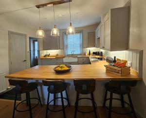 a kitchen with a wooden island with a bowl of fruit on it at Balnain Street Cottage in Inverness +14 photos
