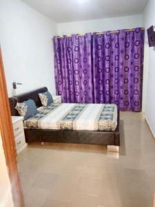 a bedroom with a bed and purple curtains at Spacious Apartment with Pool in M'bour - 100 m² in Mbour