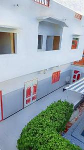 a large white building with a green bush in front of it at Spacious Apartment with Pool in M'bour - 100 m² in Mbour