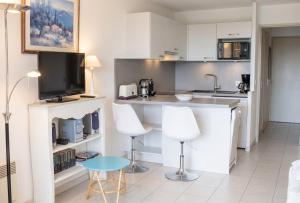a kitchen with a counter and two white chairs at Appartement convivial à Gassin 37 m² avec vue sur la mer in Gassin