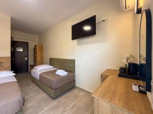 a bedroom with two beds and a tv on the wall at Celeste Blu Suites & Rooms in Paralia Katerinis