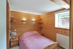 a bedroom with a bed in a wooden wall at Chalet charmant à Stosswihr avec vue sur montagne + balcon in Stosswihr