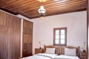 two beds in a bedroom with wooden ceilings and a window at Spacious house with sea view in Volos in Volos