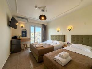 a hotel room with two beds and a television at Celeste Blu Suites & Rooms in Paralia Katerinis