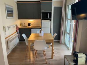 a kitchen with a wooden table and white chairs at Appartement familial avec vue sur la mer à Agay - 40 m² + piscine in Agay - Saint Raphael