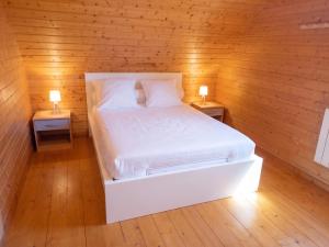 a bed in a wooden room with two lamps on tables at Chalet charmant à Saint-Gènes-Champespe avec parking privé in Saint-Genès-Champespe
