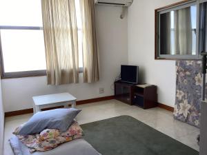 a living room with a bed and a tv at いちご荘 in Ichihara +24 photos