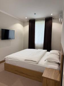 a bedroom with a bed and a television in it at Al-Amin in Termiz