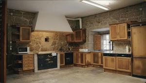 a kitchen with wooden cabinets and a large white hood at Pazo de San Pedro de Bembibre in Taboada