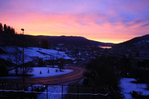 a view of a town in the snow at sunset at Studio confortable avec vue sur le lac - 30 m² - Gérardmer in Gérardmer +10 photos
