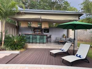 a patio with two chairs and a green umbrella at The Telescope Boutique Lodge in Victoria Falls
