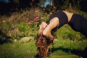 a woman with long hair doing a yoga pose in a field at Tinyhouse insolite - Au bout du chemin - 10 min de Foix in Baulou