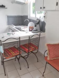 a kitchen with a table with two chairs and a stove at Bungalow cosy à Sainte-Rose, piscine et vue sur jardin. in Sainte-Rose