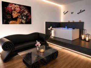 ein Wohnzimmer mit schwarzem Sofa und einem Tisch in der Unterkunft Privat-Spa mit Whirlpool und Sauna in Sursee in Sursee