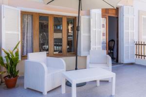a patio with two chairs and a table and an umbrella at House by the sea in Can Picafort with terrace in Can Picafort