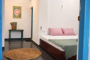 a small bedroom with a bed with pink and green sheets at Zen Yoga & Surf House in Arugam Bay