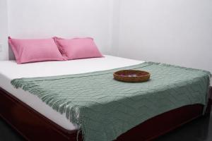 a bed with pink pillows and a basket on it at Zen Yoga & Surf House in Arugam Bay