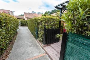 a green fence next to a walkway with plants at Maison conviviale à Argelès-sur-Mer avec piscine partagee 35 m² in Argelès-sur-Mer