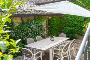 a white table with chairs and an umbrella at Quaint house in Murlo with shared pool in Murlo