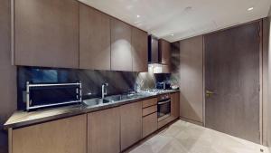 a kitchen with wooden cabinets and a stainless steel sink at Vacationer Holiday Homes I Luxurious 3 Bedroom I Iconic FIVE Palm in Dubai