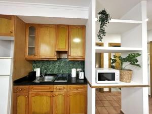 a kitchen with wooden cabinets and a microwave at Cisne del Mar ComoTuCasa in Castellón de la Plana