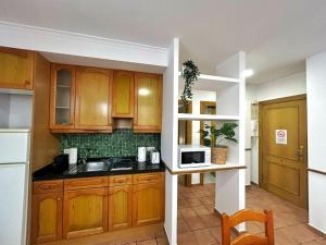 a kitchen with wooden cabinets and a microwave at Cisne del Mar ComoTuCasa in Castellón de la Plana
