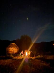 a couple of people sitting around a fire in front of a tent at Qurmety camp in Kurmenty +7 photos