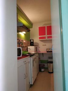 a small kitchen with red and green cabinets at Studio confortable à Cauterets - 40 m² - Vue sur la montagne in Cauterets