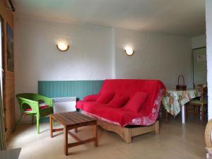 a living room with a red couch and a table at Studio confortable à Cauterets - 40 m² - Vue sur la montagne in Cauterets