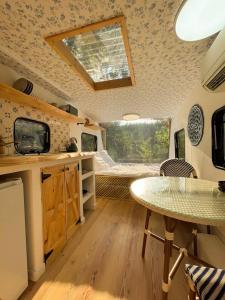 eine Küche mit einem Tisch und ein Zimmer mit einem Bett in der Unterkunft Cherry Tree Caravan in Podentes