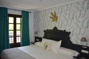 a bedroom with a white bed with green curtains at Hotel El Jisu in Camaleño +48 photos