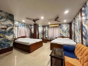 two beds in a room with paintings on the walls at Ankita Guest House Dankuni in Khorel